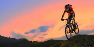 Cycliste en VTT sur un chemin de montagne au soleil couchant